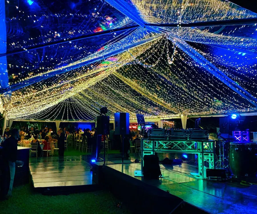 La carpa transparente de noche, con luces cálidas en el techo y pista iluminada