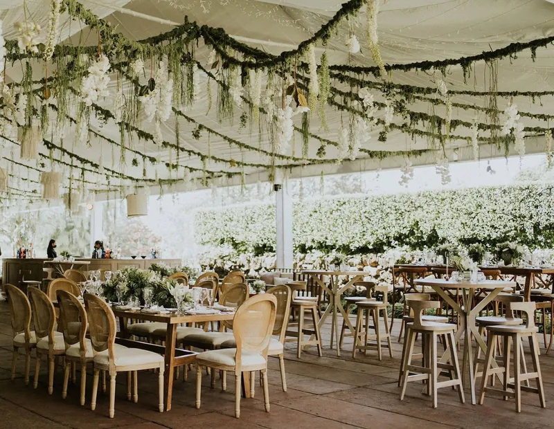 Salón montado con flores blancas colgando del techo y mesas de madera